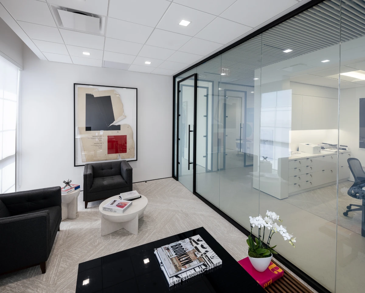 Gemini said Modern office lounge with black-framed glass partitions, minimalist gray armchairs, and contemporary wall art. 